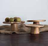 Three wooden cake stands are on a wooden table with a burlap table runner. One cake stand is displaying kiwis.