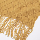 Close up of yellow throw blanket to show the diamond pattern, the texture, and the fringe on the edge.