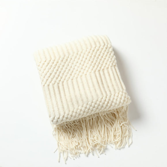 White throw blanket with alternating rows of vertical columns and dots. Blanket has wide fringe on the top and bottom.