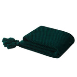 Folded dark green chunky knit throw blanket.