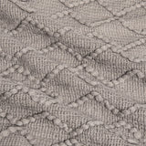 Up close image showing the colour, pattern, and texture details of the light grey throw blanket.